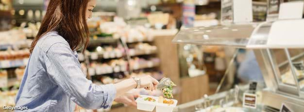 Young woman buying prepared food in supermarket