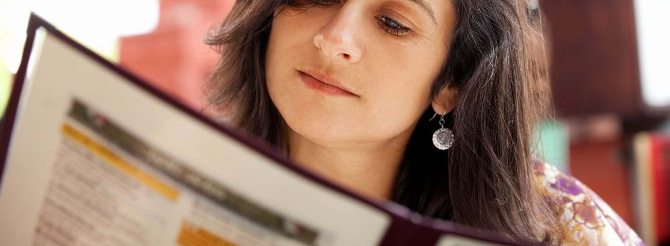 Photo of woman reading a restaurant menu.