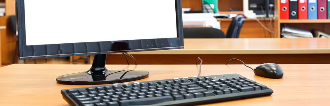 Computer monitor, keyboard, and mouse on desk in office