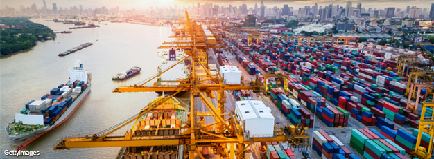 Photo of a container cargo ship with working crane bridge in shipyard