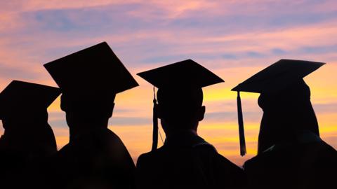 Silhouettes of students with graduate caps and gowns