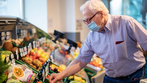 Man in mask shopping in produce department