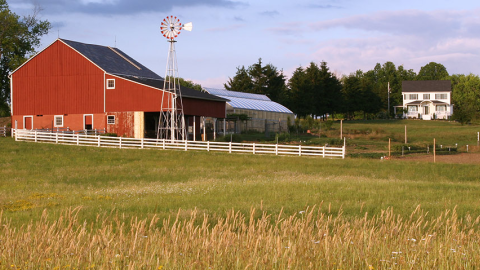 Photo of red barn with white farm house in background