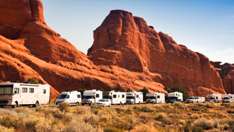 Photo of a line of recreational vehicles with mountains in the background.