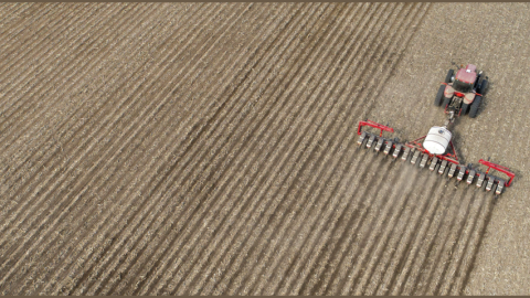 Photo of a crop field being sown with a planting machine.